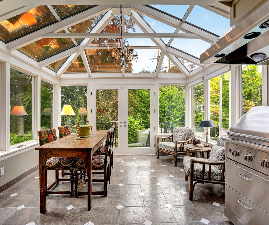 Remodeled sunroom by AKN Interiors in Greater Pittsburgh, PA with glass walls, wood table, grill, and garden view.